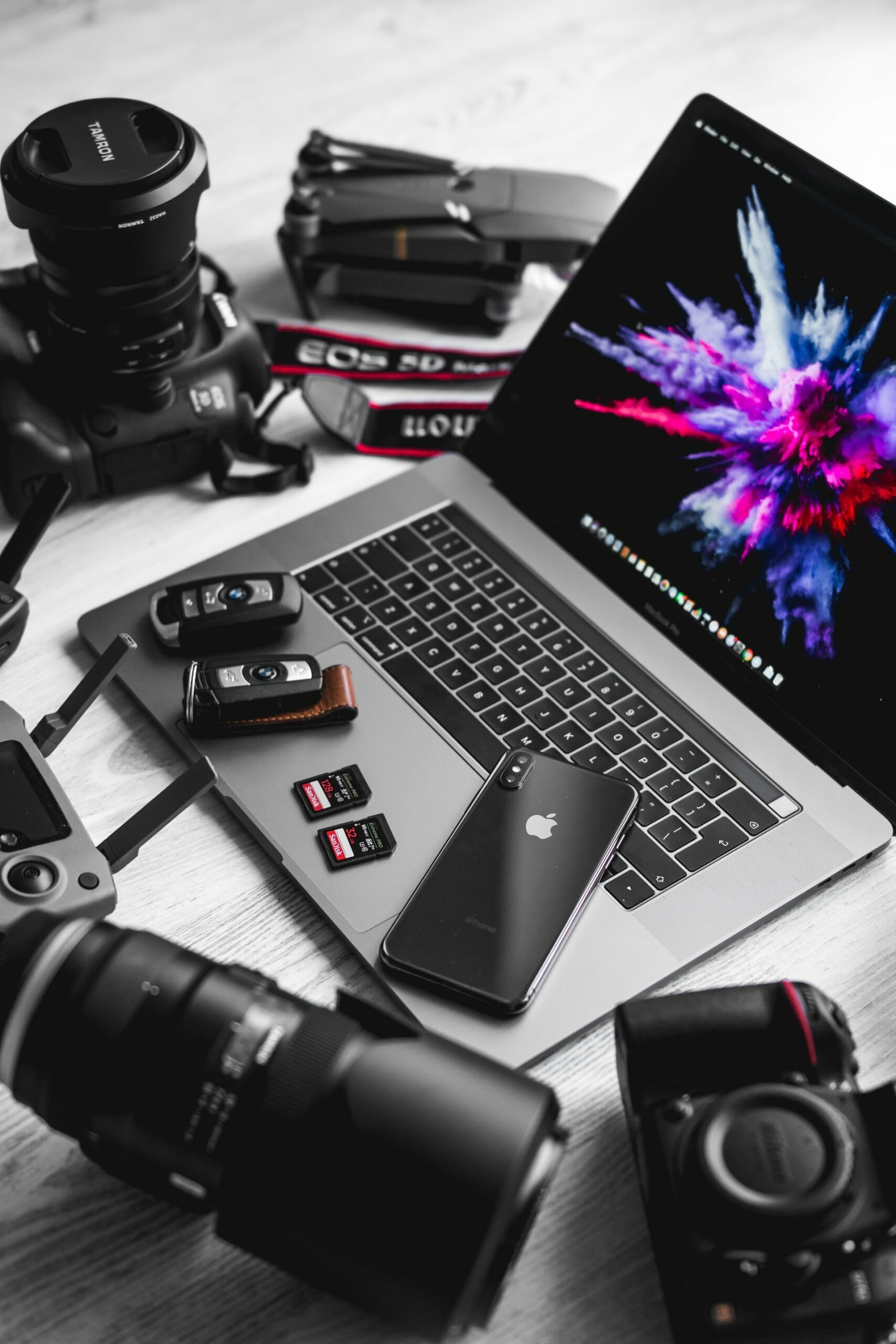 Photo with MacBook Pro, camera equipment, cellphone and car keys