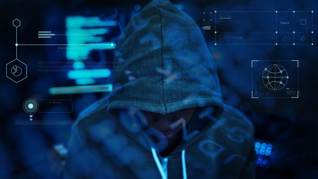 person with hoodie slightly over face and coding in background
