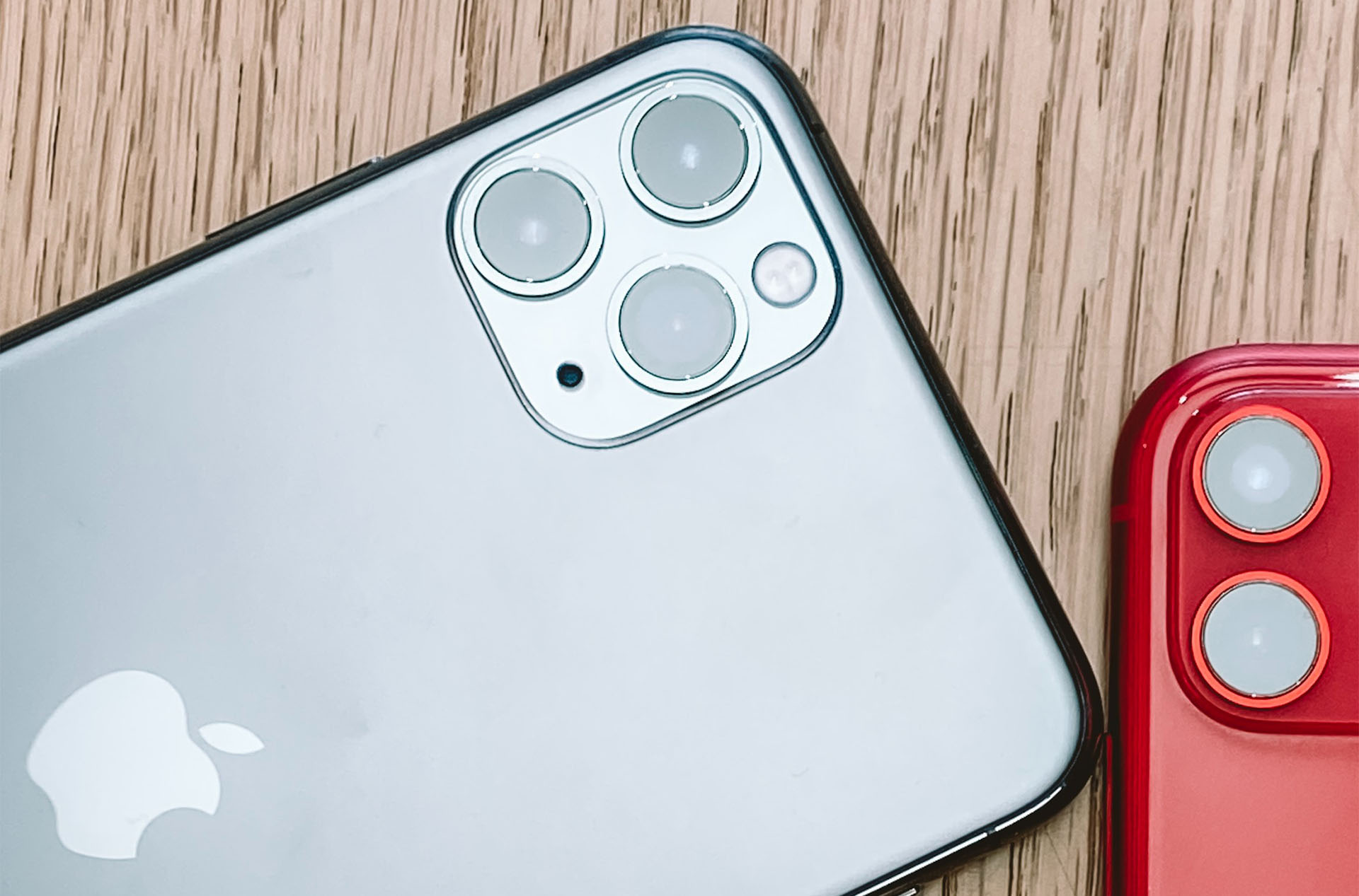 Photo of the back sides of a silver iPhone 11 Pro and a red iPhone 11