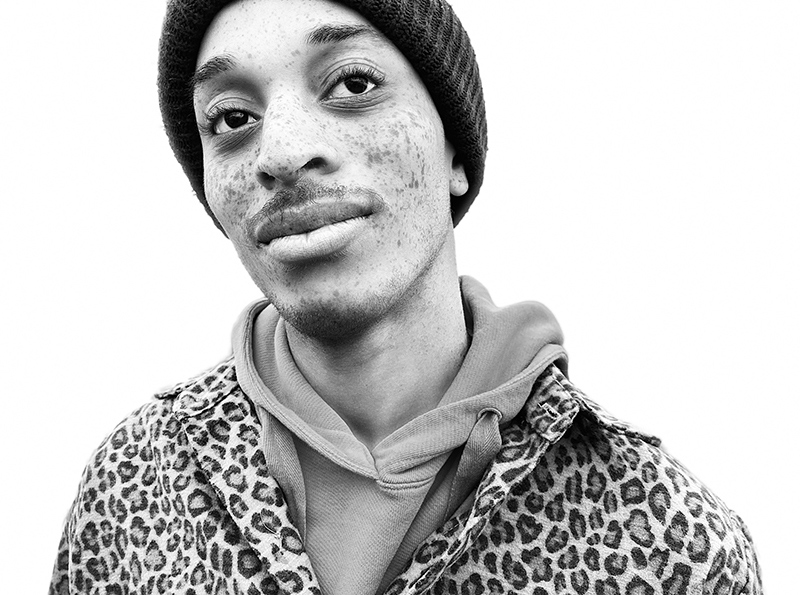 Shot with portrait mode on the iPhone S E using the mono filter. Man with freckles wearing beanie and tiger spotted hoodie